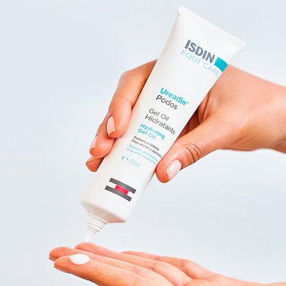 Hand holding a tube of ISDIN Ureadin Podos moisturizing gel on a light gray background
