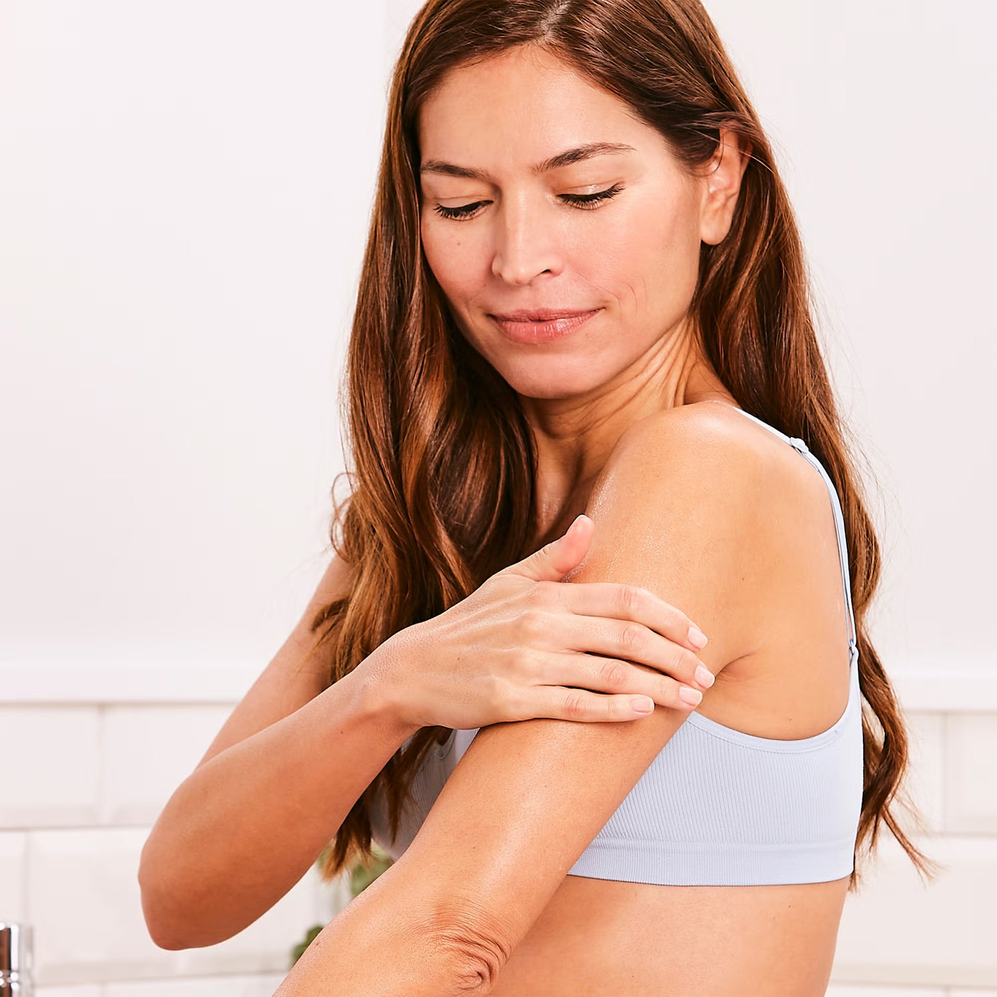 Woman examining her arm against a white background