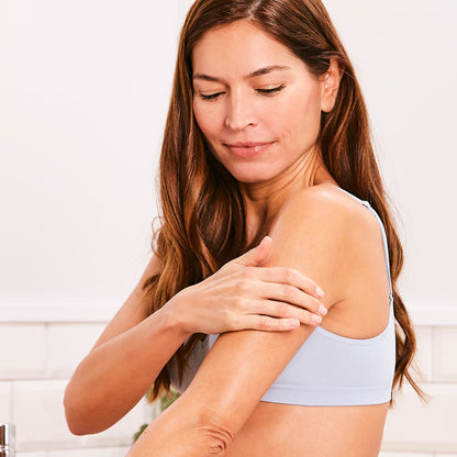 Woman examining her arm against a white background