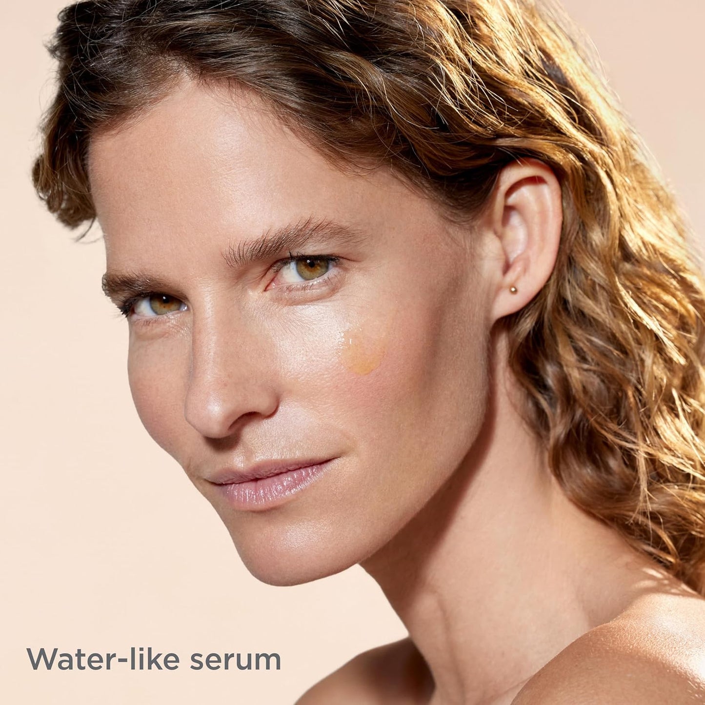 Woman with a water-like serum applied to her face on a beige background
