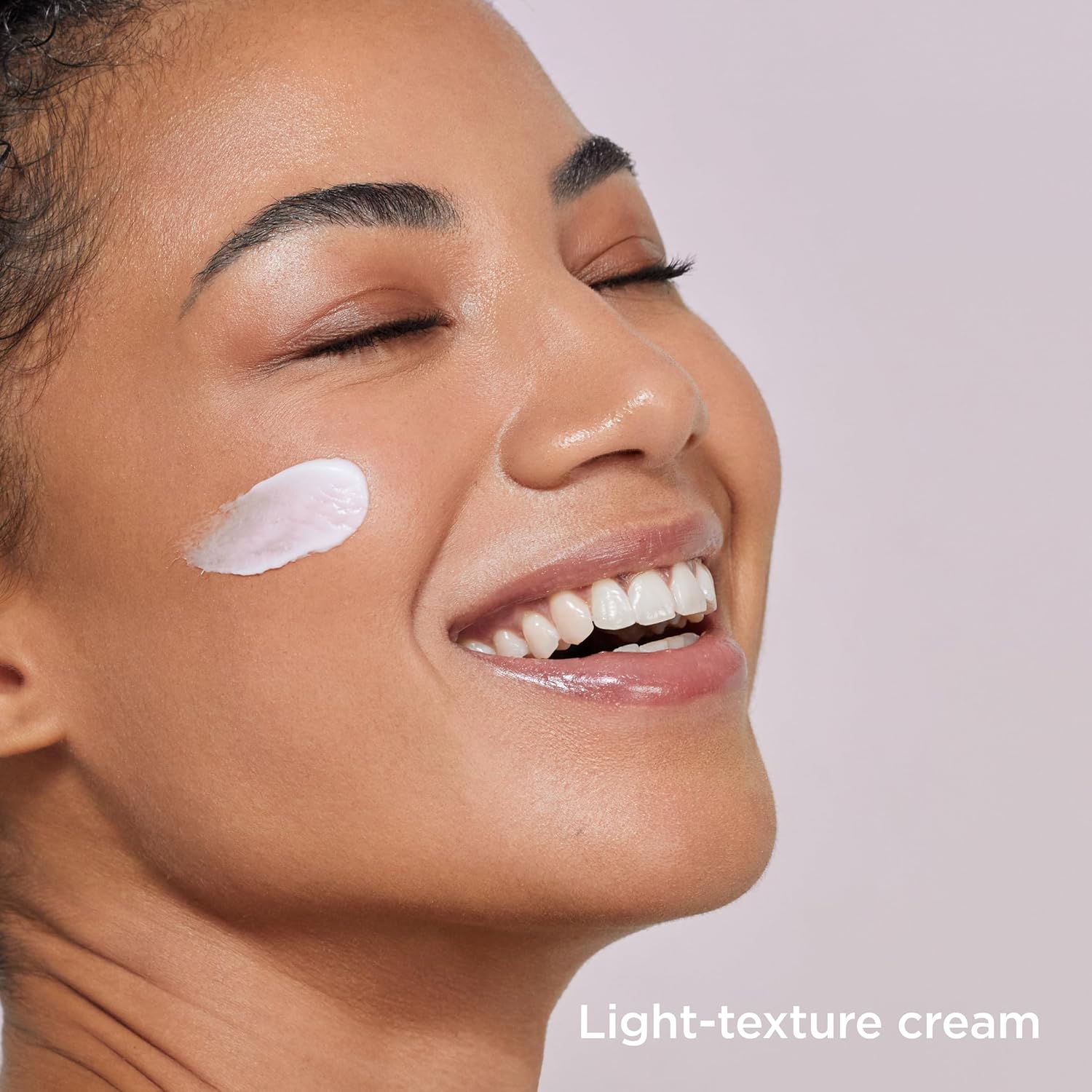 Woman applying light-texture cream to her face with a neutral background