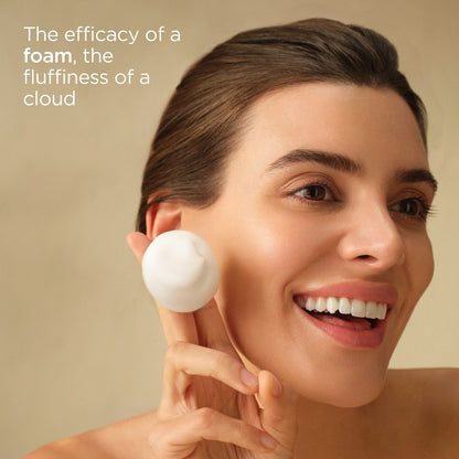 Woman using a white foam product on her face with a beige background and text about foam and cloud fluffiness.