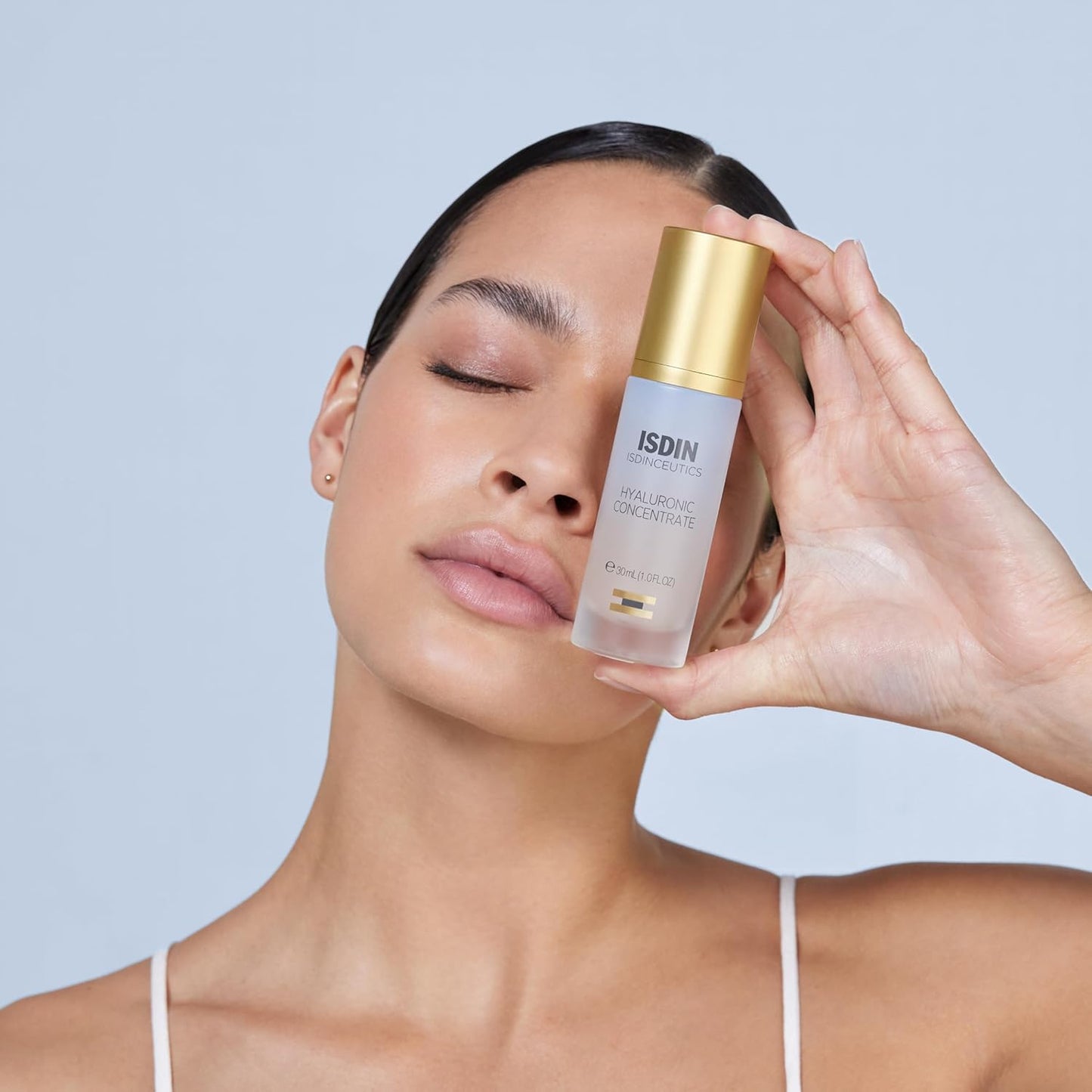 Woman holding a skincare product with a plain background