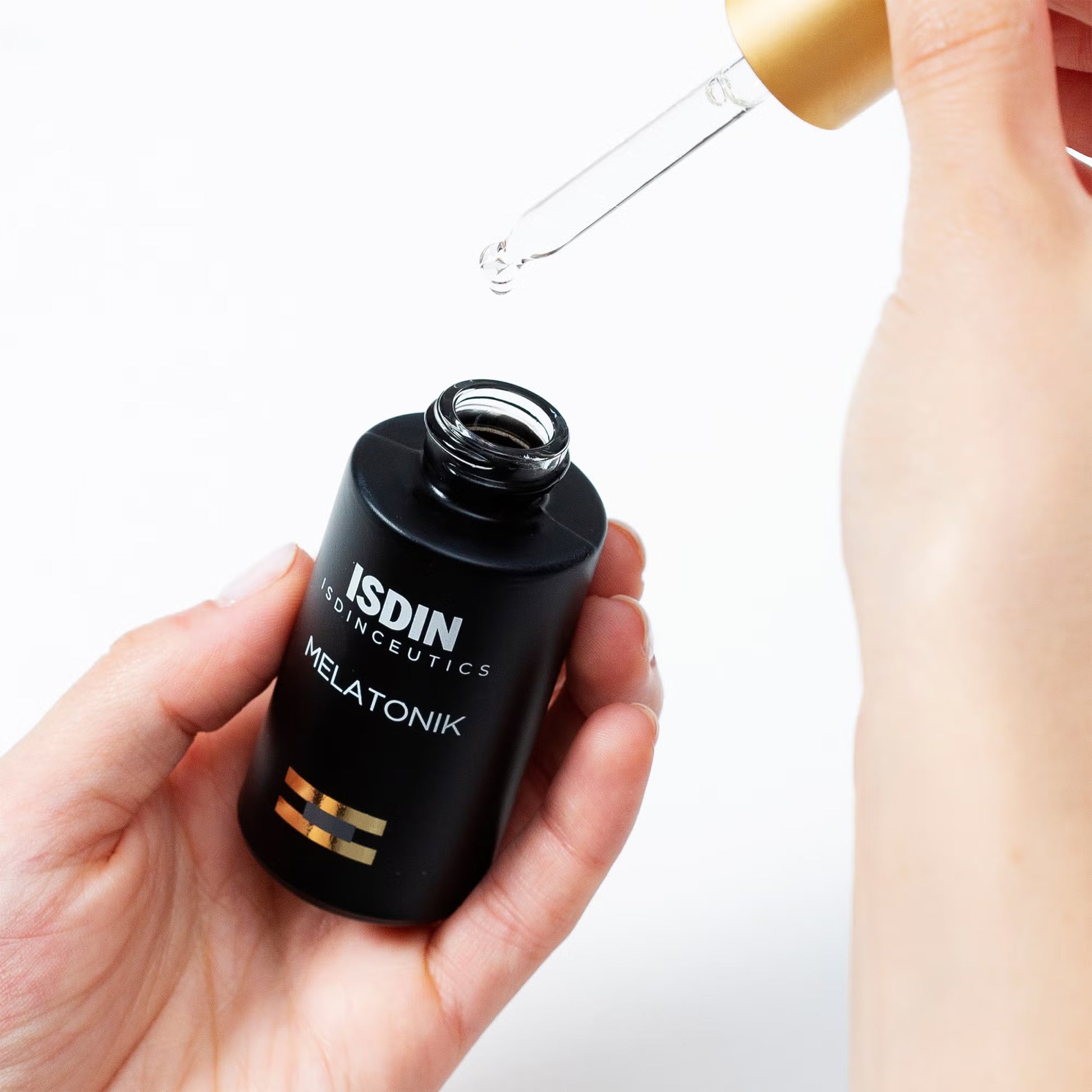 ISDIN Melatonik skincare product with dropper held by a hand on a white background