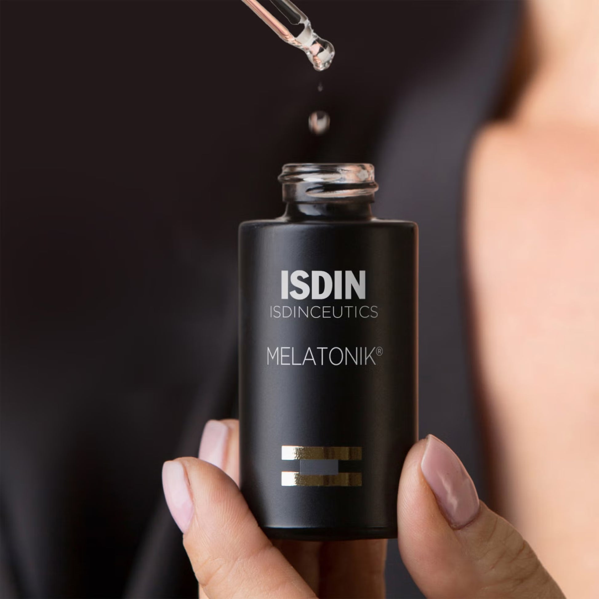 ISDIN ISDINCEUTICS MELATONIK bottle with dropper held by a hand against a dark background